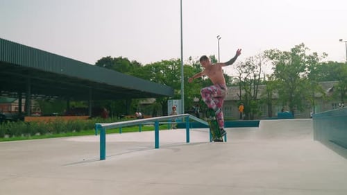 Young Adult Skateboarder Rides Rail in Skate Park