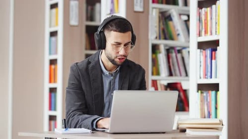 Young Man with Headphones Dancing in Front of Laptop