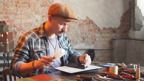 Man Working Leather with Hammer at Workshop