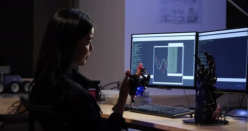 Young girl developing software and testing robotic arm