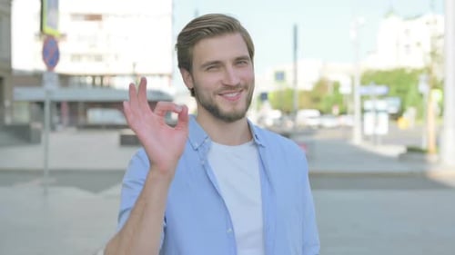 Man Smiling and Giving OK Hand Gesture in City