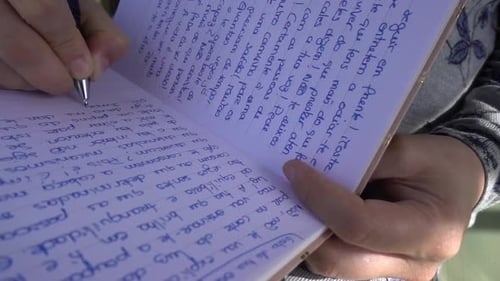 Woman's Hands Writing in a Journal Outdoors