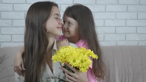 Girl Hugging Young Woman with Yellow Flowers