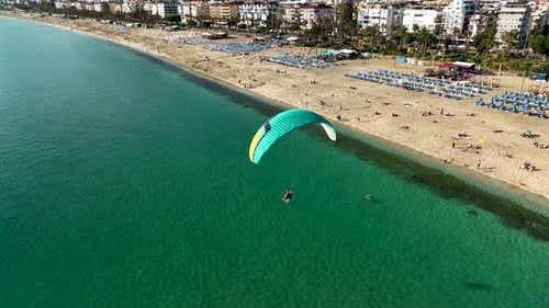 Aerial drone view of parachute jumper flying over beautiful beach