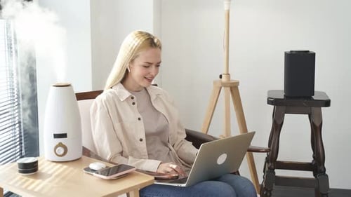 Woman Using Laptop Computer With Humidifier at Home