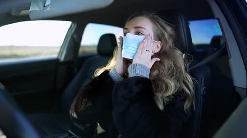 Woman Putting On Face Mask in Her Car