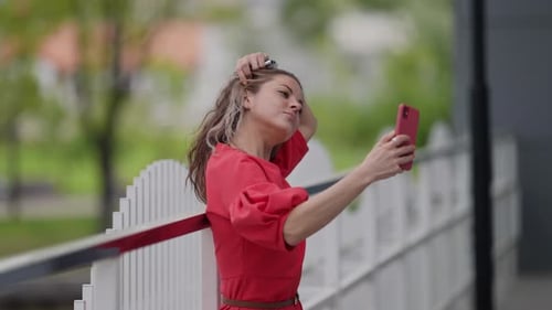 Young Woman with Modern Gadget is Taking Selfie By Camera of Smartphone on Street