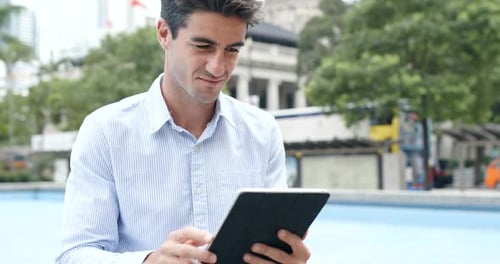 Young Adult Man Using Tablet in Urban Park