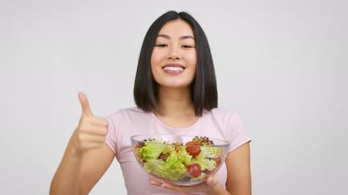 Young Woman Holding Salad Giving Thumbs Up