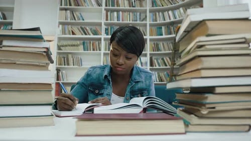 Focused Student Studying with Books in Library