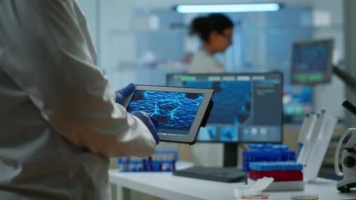 Cierre de científico en bata de laboratorio trabajando con tableta