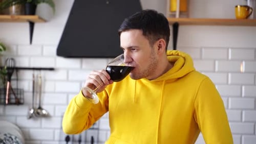 Man in Yellow Hoodie Drinking Red Wine Indoors