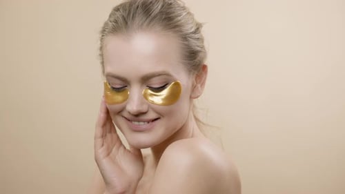 Attractive Woman with Golden Eye Patches Smiling