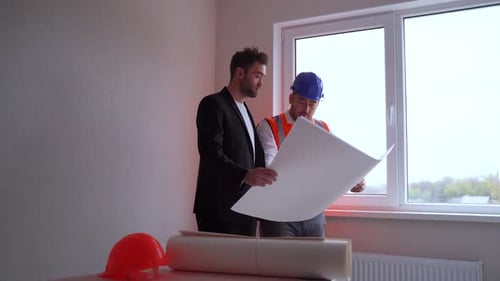 Construction Workers Reviewing Blueprints on Construction Site