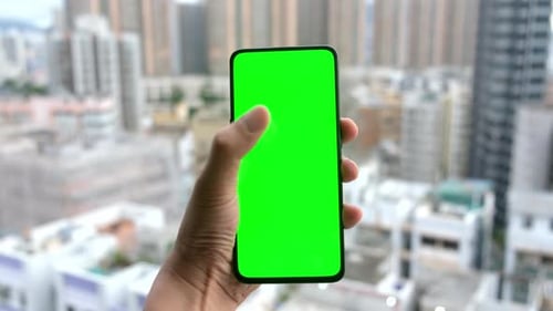 Male hands using smartphone with green screen.