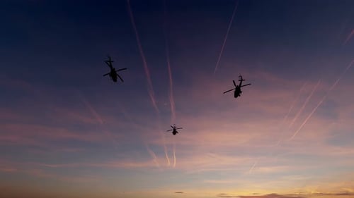 Multiple Helicopters Flying at Sunset in Silhouette