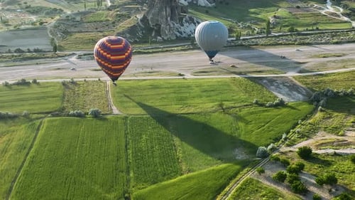 Hot air balloons fly over the mountainous landscape of Cappadocia, Turkey.