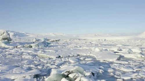 AERIAL: Flying Over White, Blue Snowy Ice Floes on Iceland Lake Winter, Snow