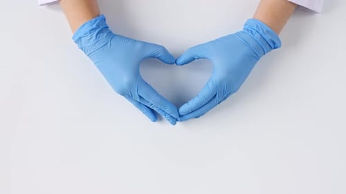 Gloved Hands Forming Heart Symbol on White Background