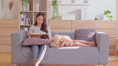 Mother Reading Book to Child on Couch