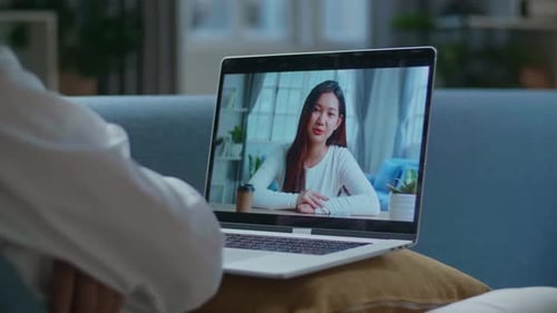 Close Up Of A Man Having Video Call With A Woman On Laptop While Lying On Sofa In The Living Room