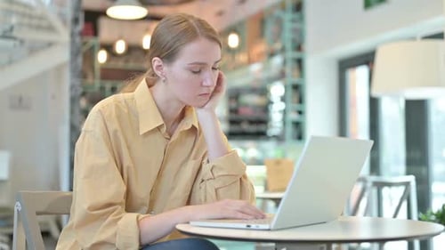 Young Woman with Laptop Taking Nap in Cafe