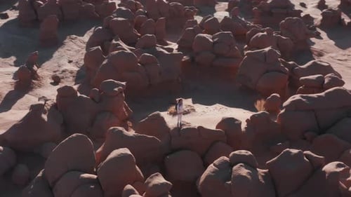 Woman Standing Among Red Rocks in Desert Landscape