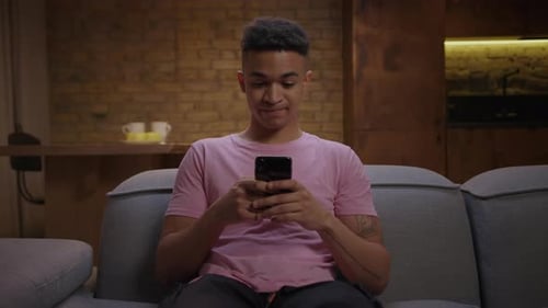 Young Adult Using Mobile Phone on Sofa