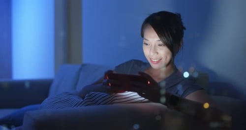 Woman Using Smartphone on Couch at Night