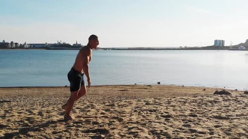 Young Man Running Up and Starts Doing a Series of Flips on the Beach