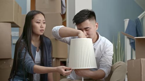 Couple Turning on New Lamp after Moving House