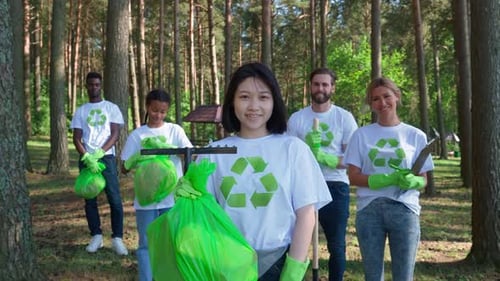 Volunteers Holding Trash Bags in Sunny Forest