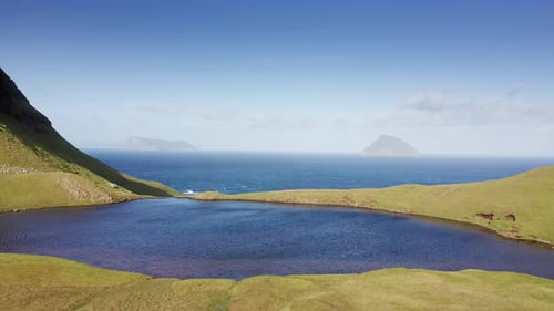 Aerial View of Cliff Covered in Grass Blue Sea Sun Clouds