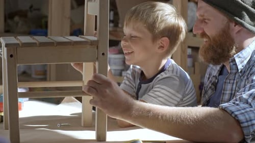 Child Assembling Chair with Adult in Workshop
