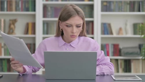 Woman with Laptop Reading Documents in Office