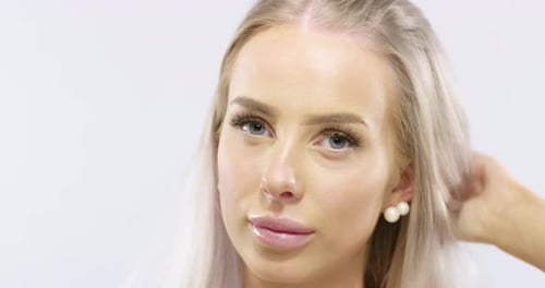 Close-up Portrait of a Smiling Young Woman Touching Her Blonde Hair