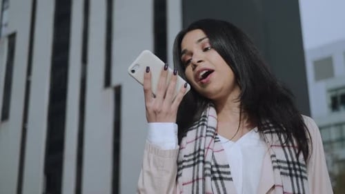 Serious Businesswoman Recording Voice Message on Smartphone at City Street
