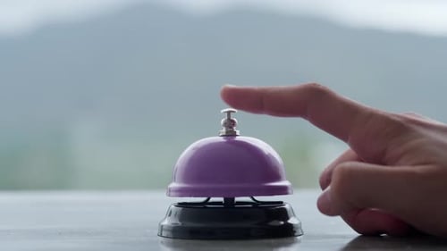 Close Up of Hand Ringing Purple Service Bell