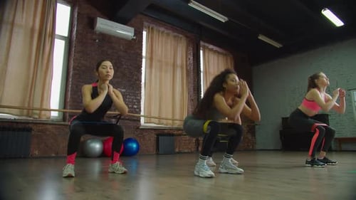Femmes en forme variée faisant des squats avec bande de résistance
