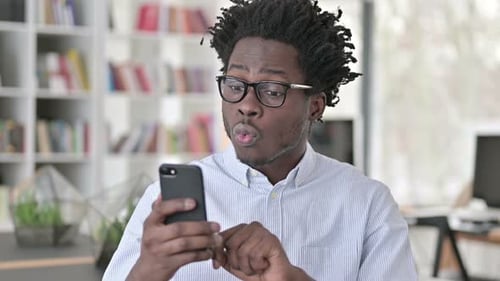 Man Cheers while Looking at Smartphone Inside