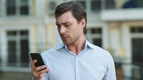 Portrait Man Using Smartphone Outdoor. Man Typing on Cellphone at Street
