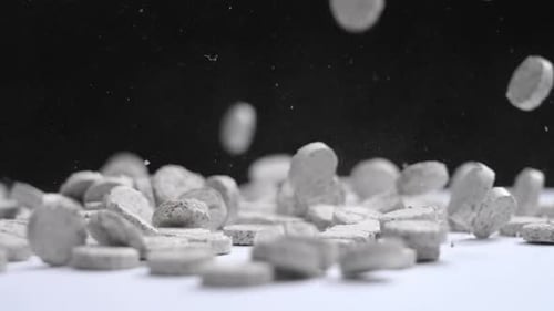 Gray Textured Tablets Falling onto a White Surface