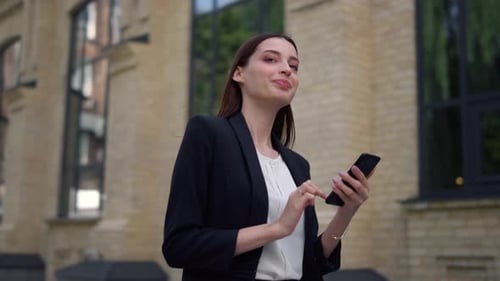 Young Woman Using Phone Walking in City