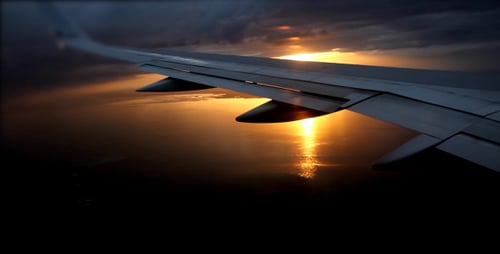 Airplane Wing at Sunset Flying Over City