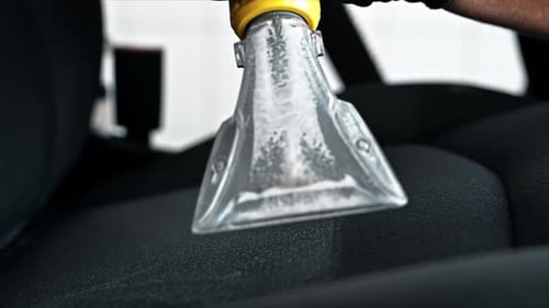 Working cleaner at car wash. Cleaning a seat using a professional vacuum cleaner. Slow motion