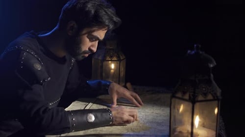 Man in Dark Room Examines Map by Lantern Light