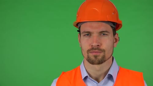 A Young Construction Worker Looks Seriously at the Camera - Closeup - Green Screen Studio