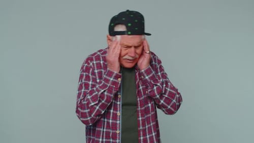 Senior Man Rubbing Temples in Discomfort