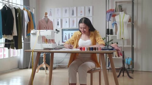 Smiling Asian Female Designer With Sewing Machine Enjoy Designing Clothes In The Studio