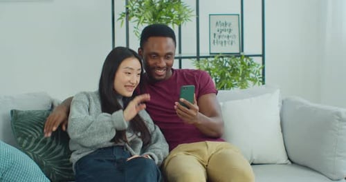 Cheerful Couple Relaxing on Couch Using Phone